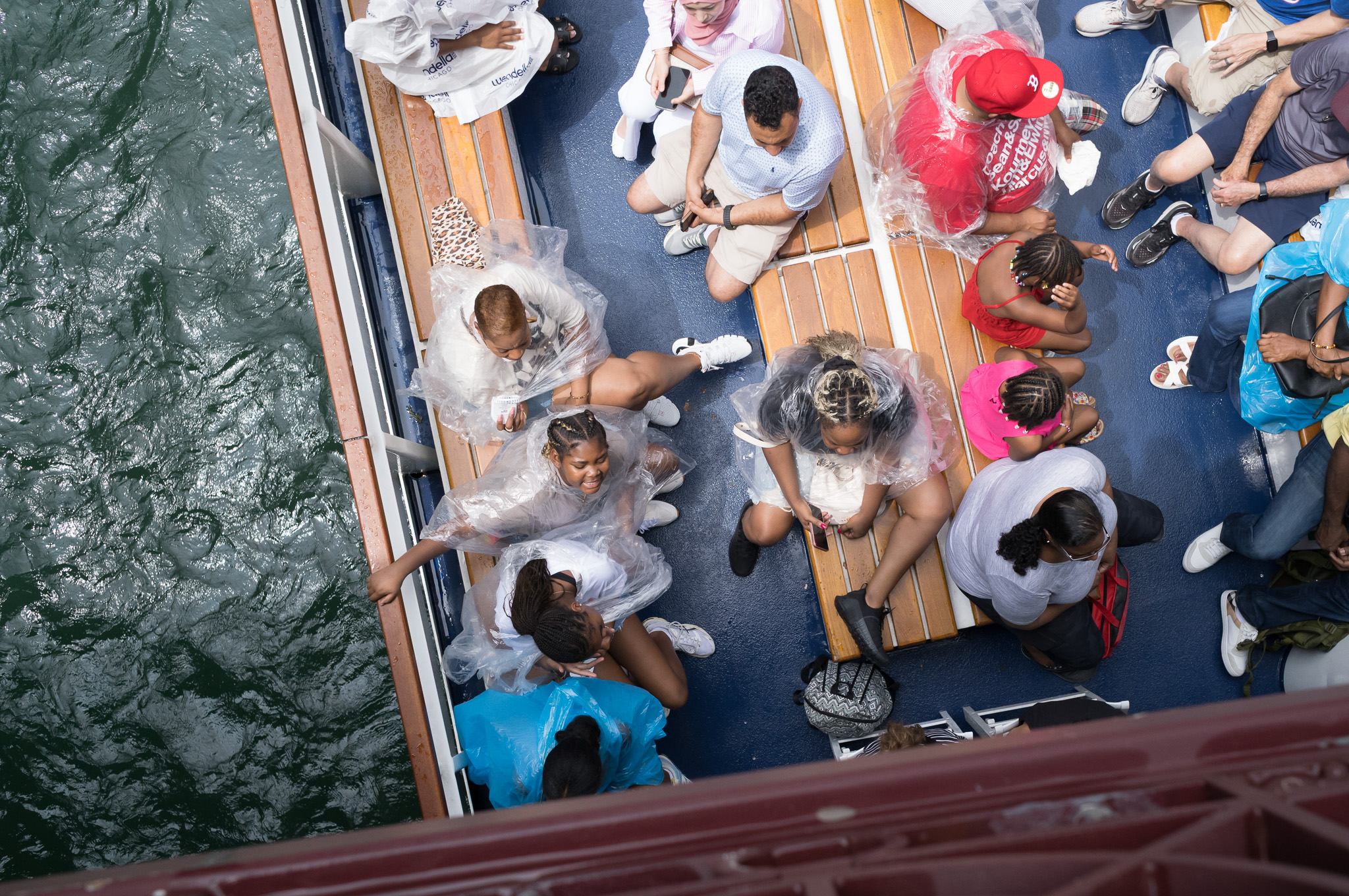 Christian Solorzano — photograph looking down from a bridge onto tour boat passengers wearing clear plastic rain ponchos