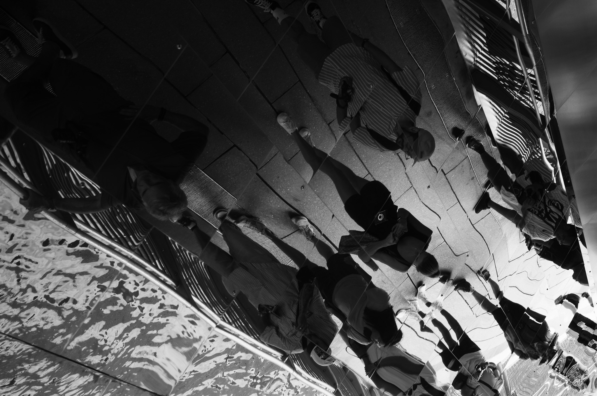 Christian Solorzano — black and white photograph of figures reflected and stretched in the mirrored surface of Cloud Gate