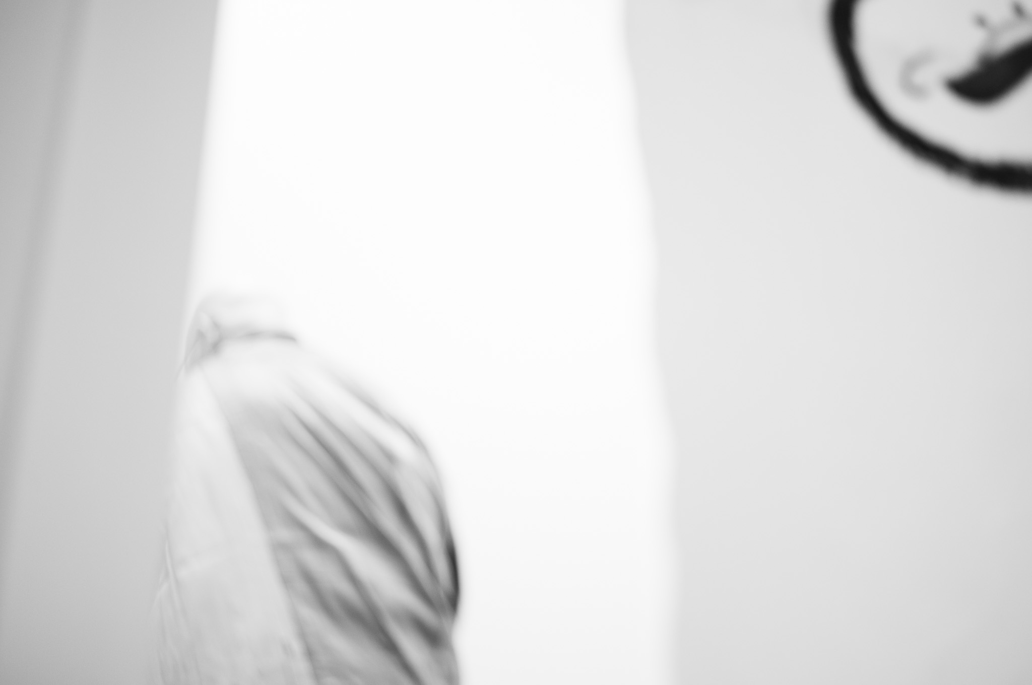 A bowed head and shoulder in white, almost lost in a wall of blown-out light, an inked enso in the corner above.