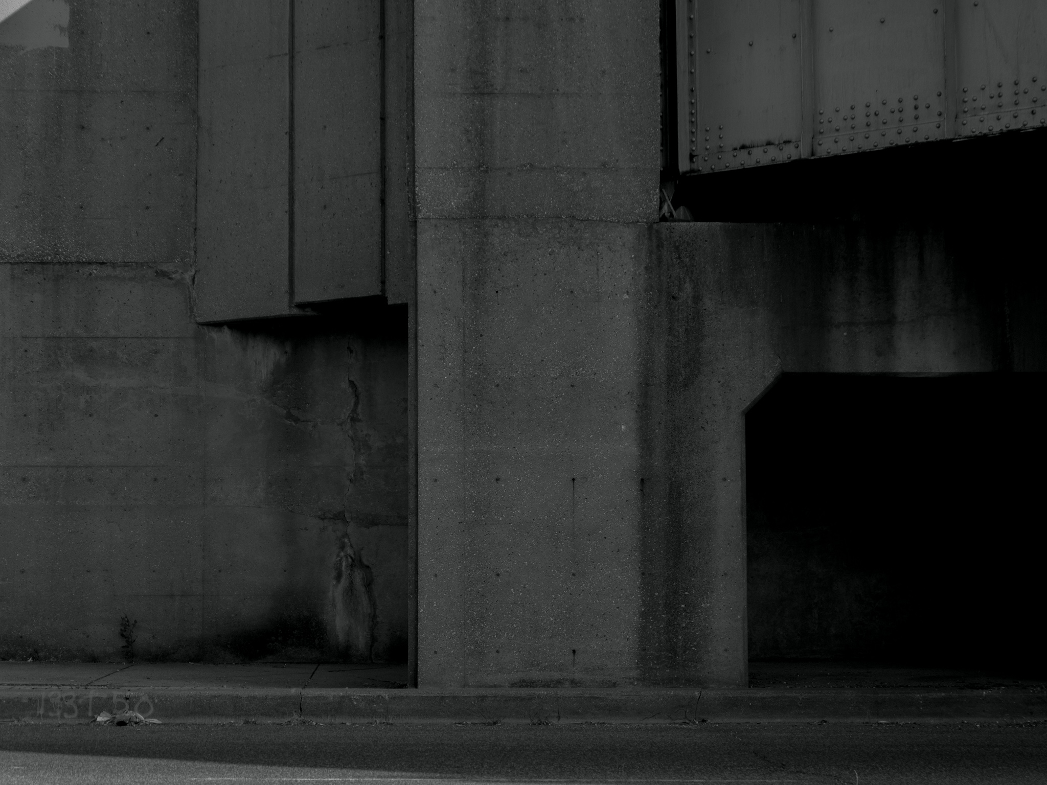 Christian Solorzano — minimal black-and-white photograph of the concrete piers and steel girders beneath a railway overpass