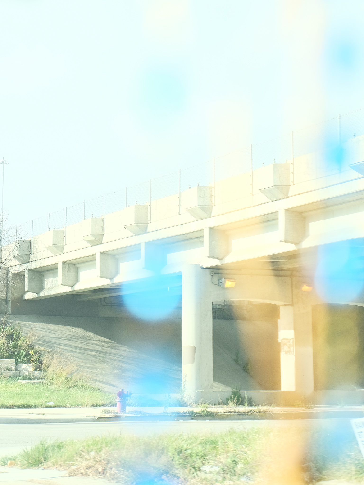 Christian Solorzano — light-leaked photograph of a concrete highway overpass and a red fire hydrant washed in bright sun