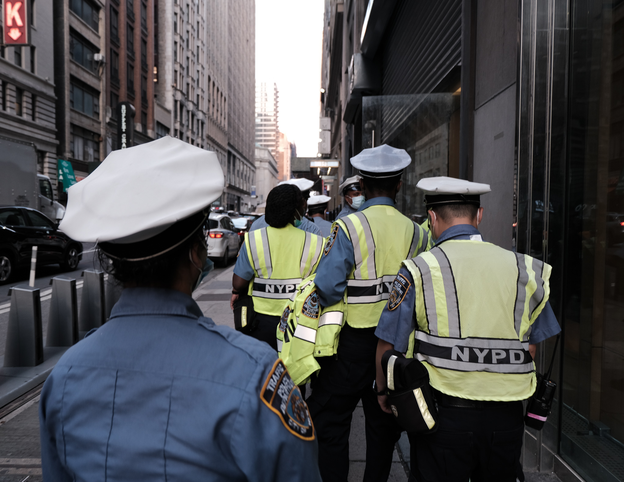 Christian Solorzano — street photograph of NYPD traffic officers in white caps and yellow vests walking a New York City block