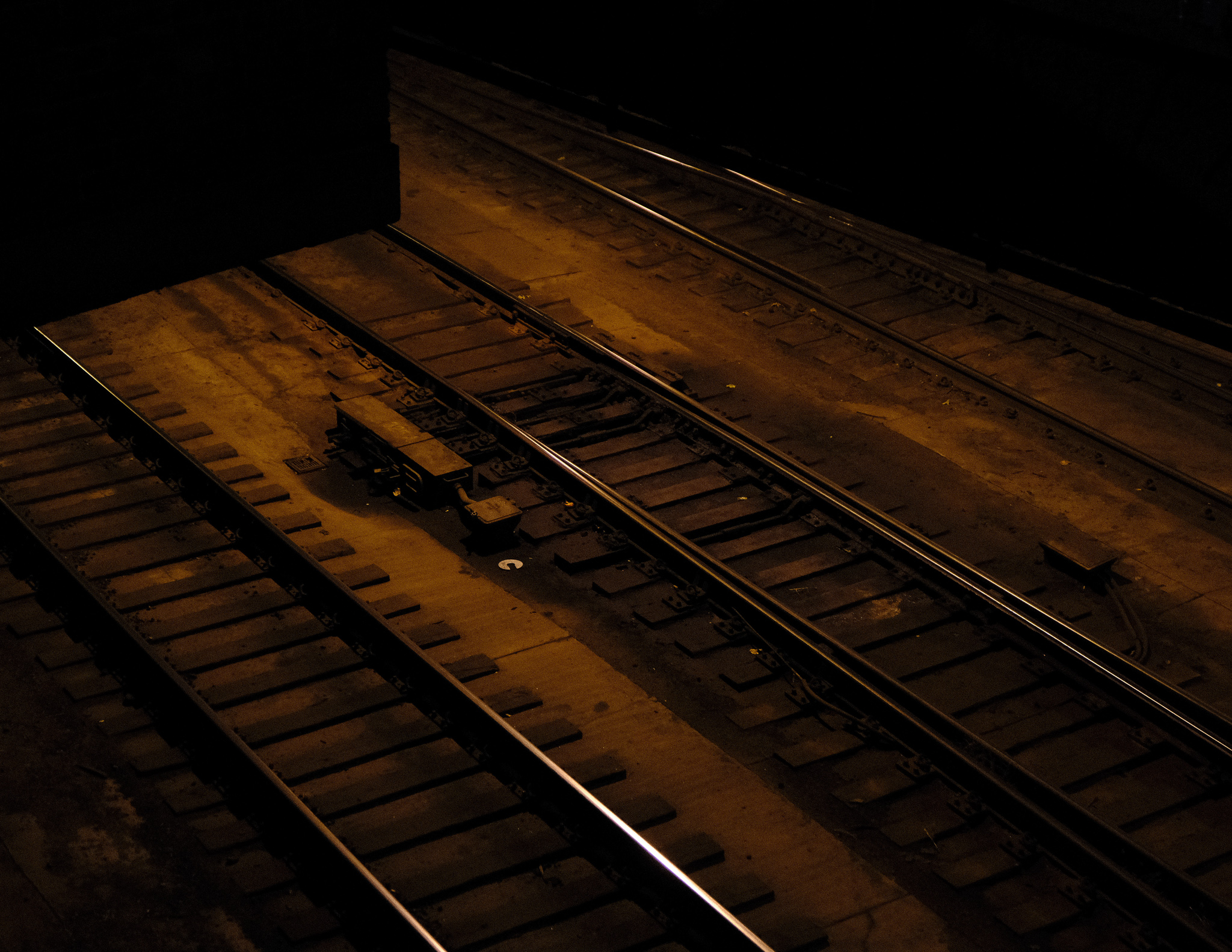 Christian Solorzano — warm-toned night photograph of railroad tracks and switch gear under amber light