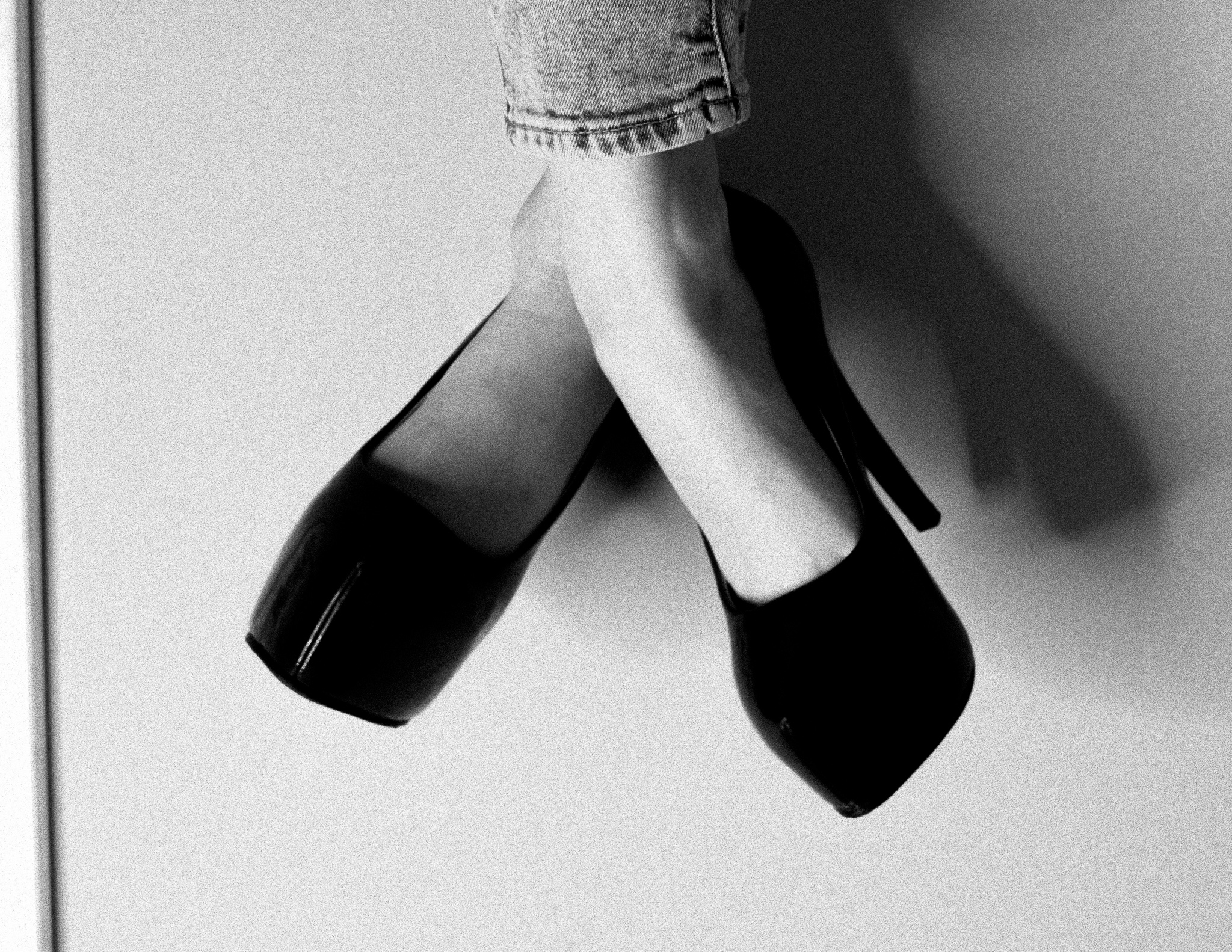 Christian Solorzano — black-and-white photograph of dangling legs in black platform high heels