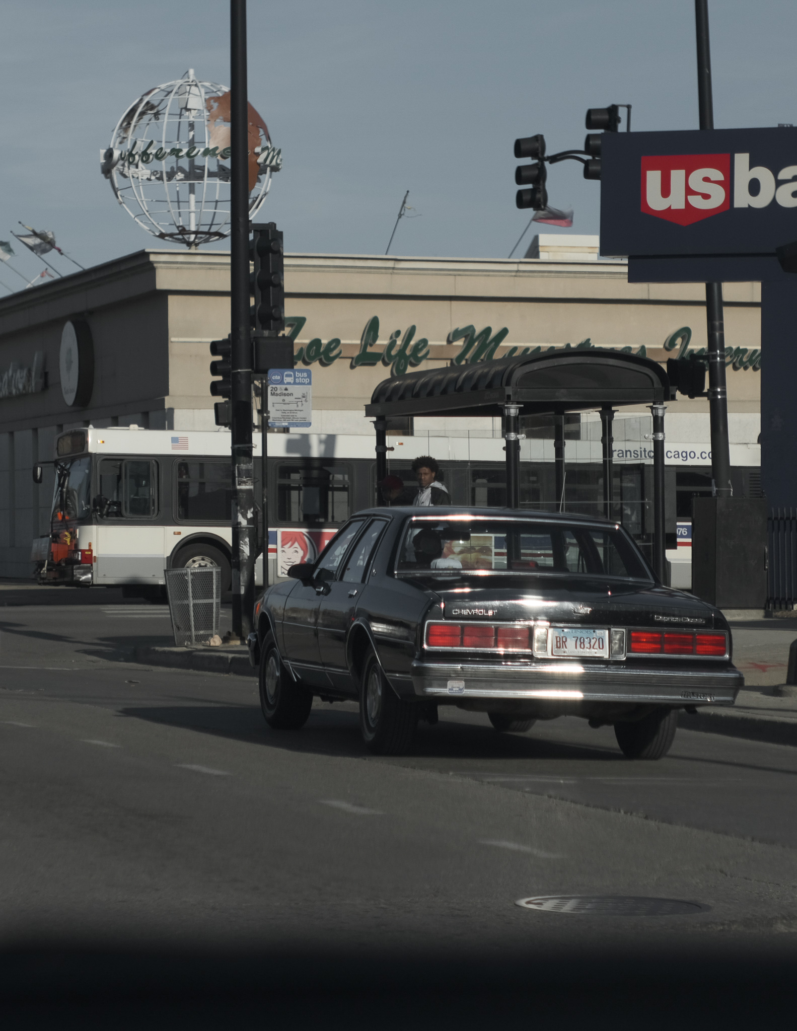 Christian Solorzano — Chicago street photograph of a black Chevrolet Caprice passing a church and US Bank sign