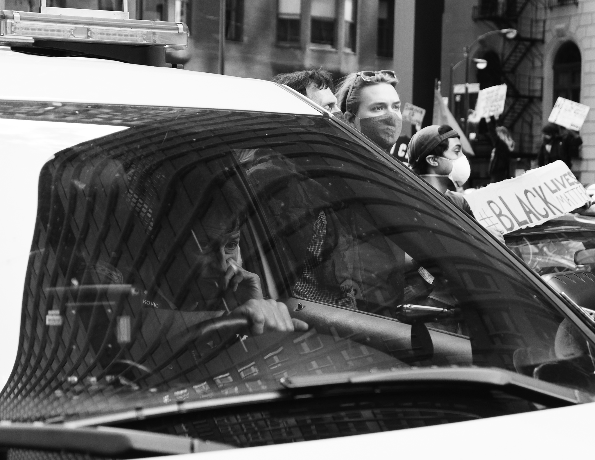 Christian Solorzano — black-and-white photograph of protesters and a Black Lives Matter sign reflected in a car window